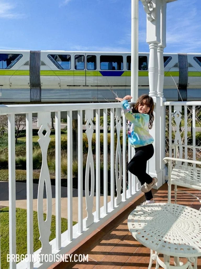 girl standing on Grand Floridian balcony watching monorail drive by